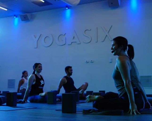 Instructor leading Yoga Six class on floor