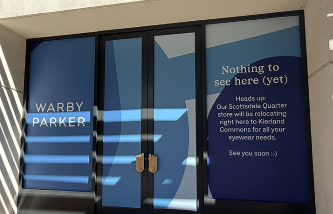 Warby Parker storefront signage announcing relocation to Kierland Commons with “Nothing to see here (yet)” message on window.