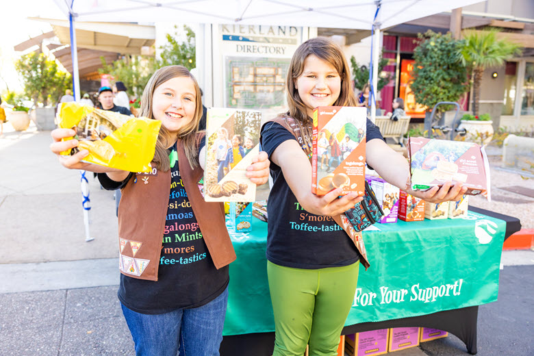 Girl Scout smilling and holding 2 boxes of cookies.