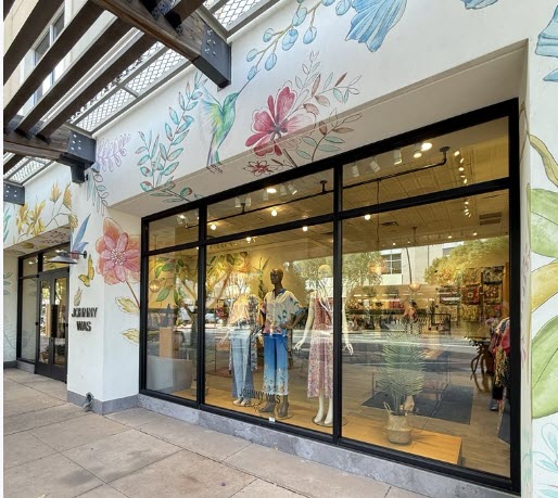 Exterior view of the Johnny Was boutique at Kierland Commons in Scottsdale, Arizona, featuring floral mural artwork and window displays with colorful bohemian-style clothing.
