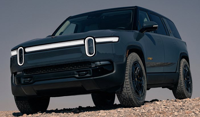 A black Rivian vehicle parked on a rocky terrain. 