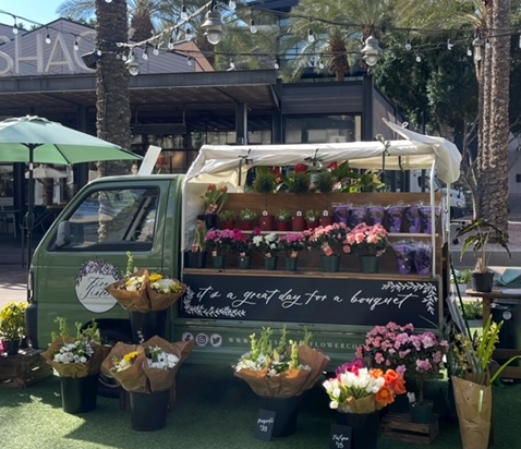 A green truck with a variety of plants and flowers displayed around it.