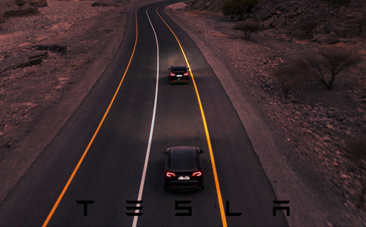 Two Tesla cars driving down a road