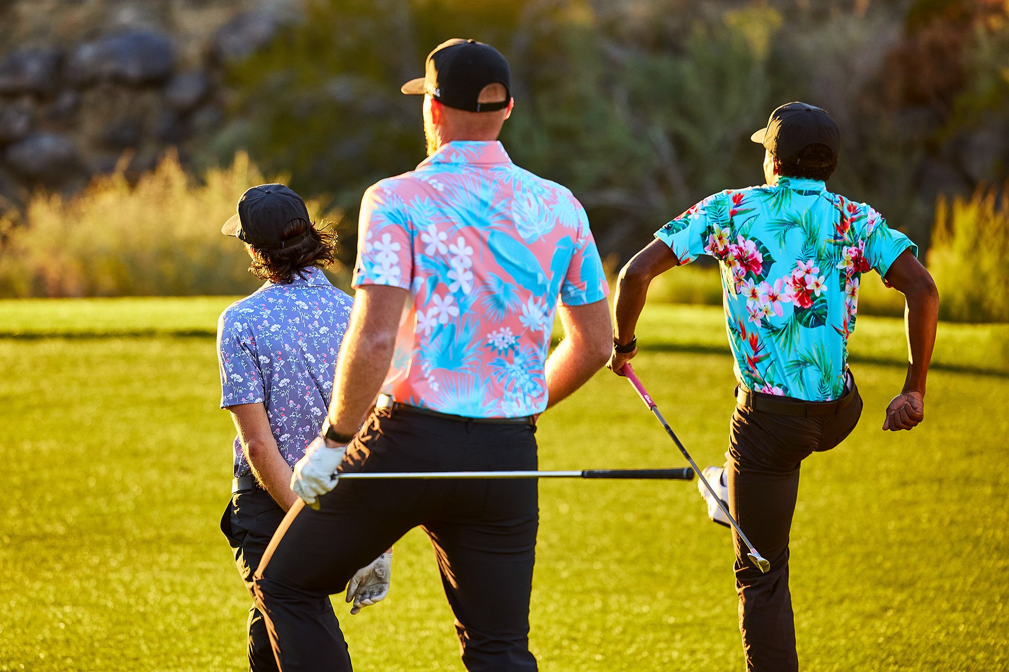 Three men holding golf clubs walking outside.