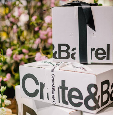 Crate & Barrel gift boxes with ribbons, displayed in front of a floral backdrop.