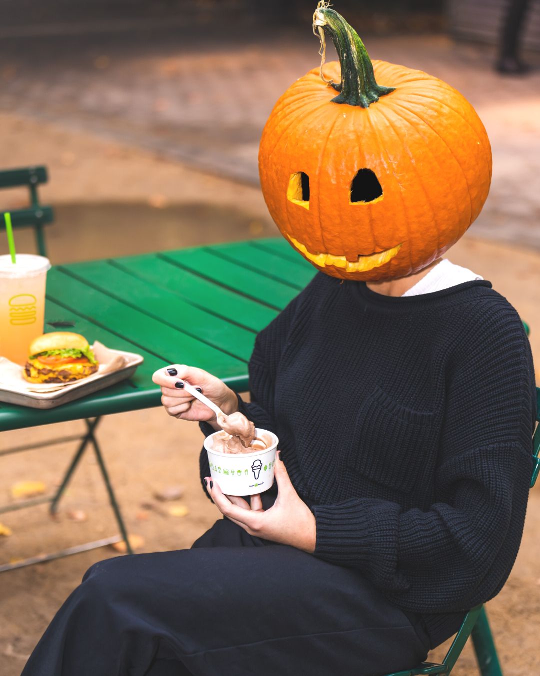 Women sitting on chair with a pumpkin head eating an ice-cream custard from Shake Shack