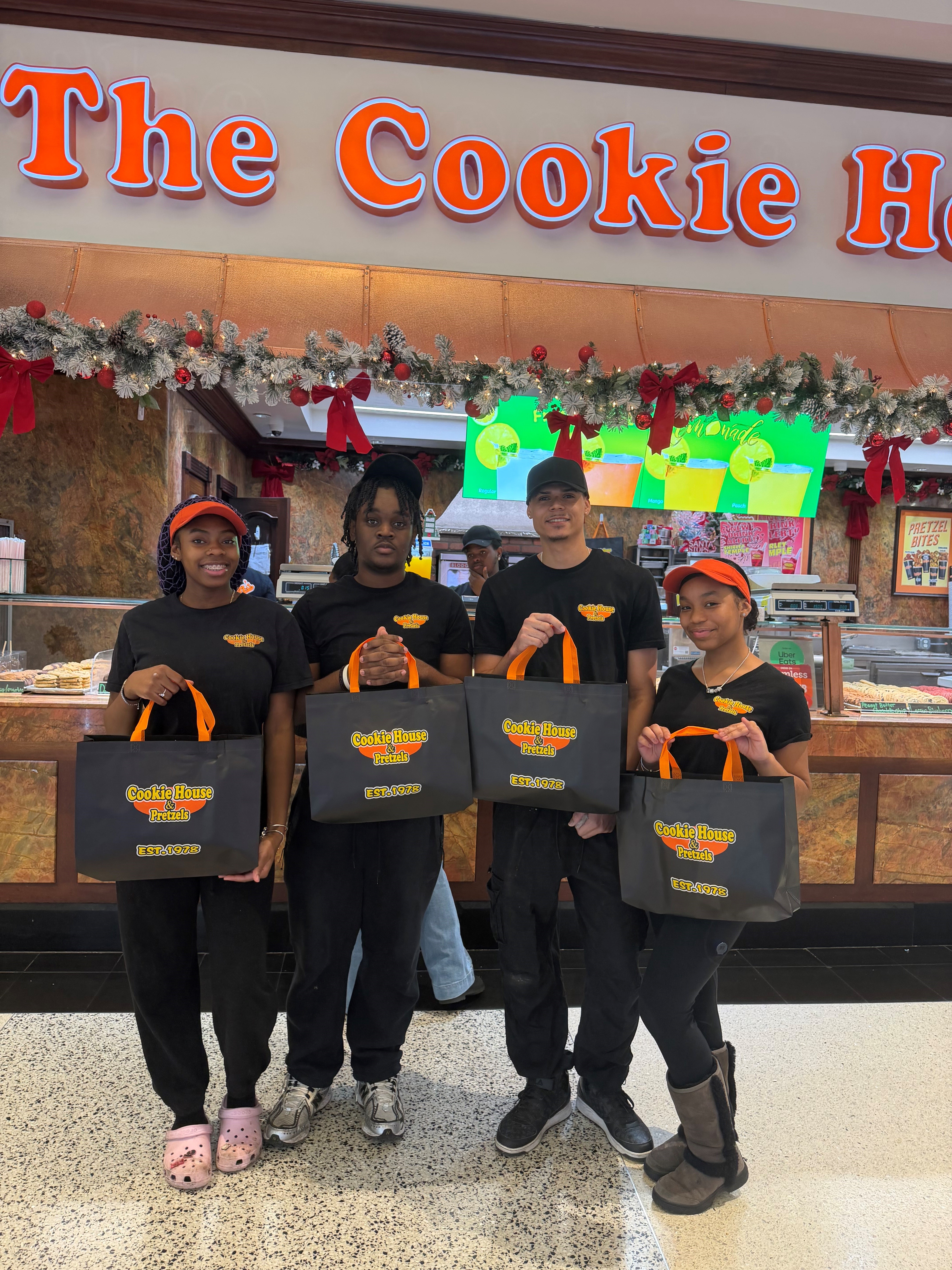 Employees from The Cookie House smiling with Cookie House bags in their hands
