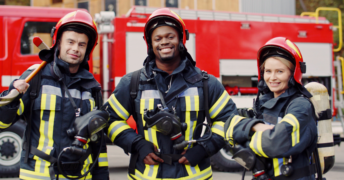Two male and one female firefighters standing in front of a fire truck. 