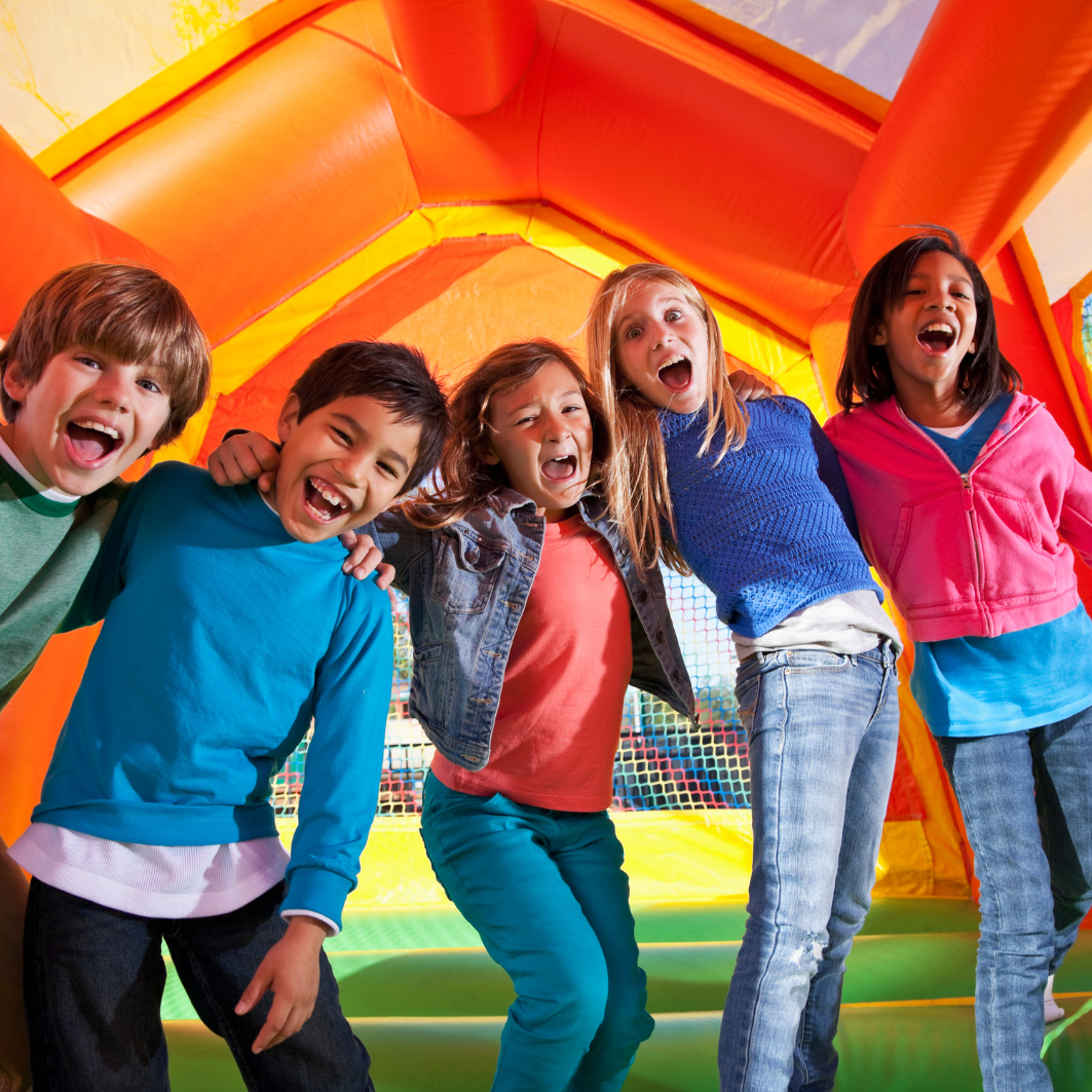 5 children smiling in a bounce house 