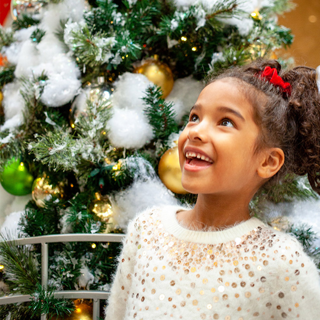 little girl smiling looking at Christmas tree