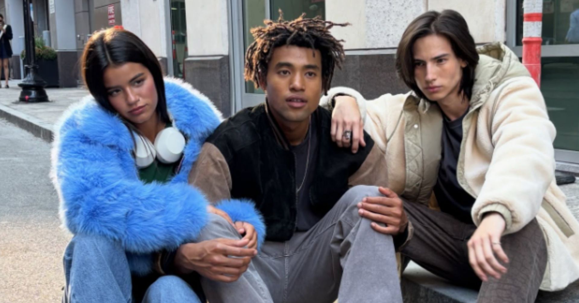 3 teens sitting on a sidewalk curb
