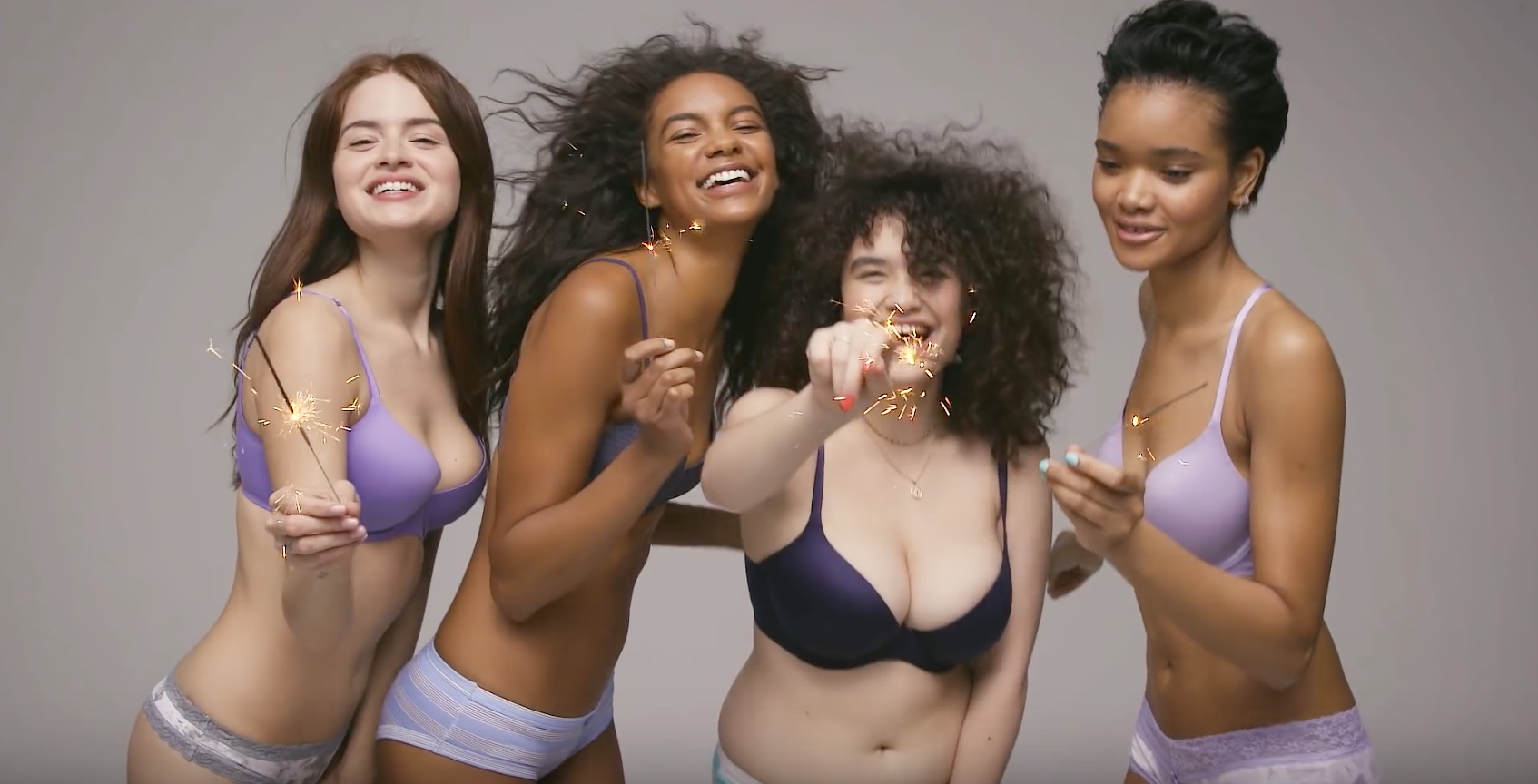 Four women in Aerie bralettes smiling and holding sparklers.