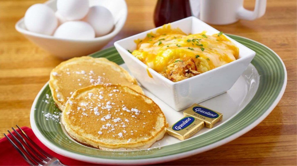 Plate of pancakes with powdered sugar on them and a square bowl with cheesy eggs