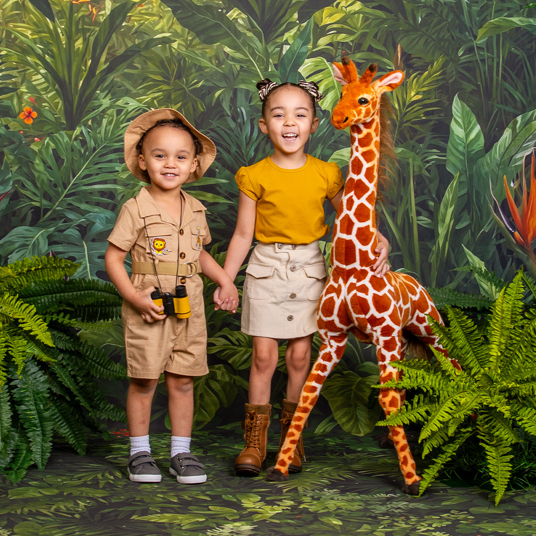 Brother and sister in jungle theme settings with stuffed animal giraffe