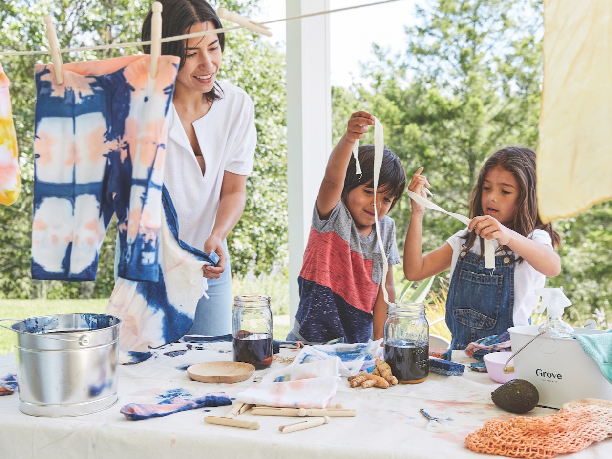 Mom with son and daughter tie-dying clothing with plant base dye in backyard