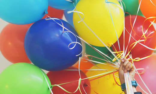Hand holding a bundle of balloons.