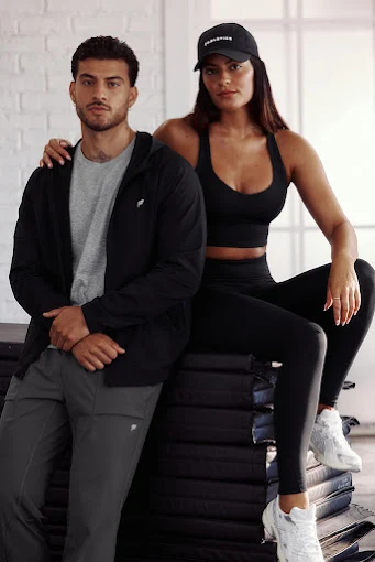 Man and woman posing on yoga mats wearing workout clothes.