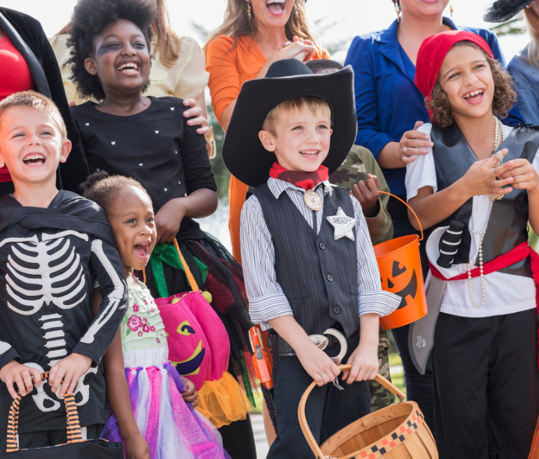 Children lined up in Halloween costumes smiling.