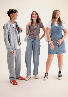 Teenagers laughing together holding backpacks.