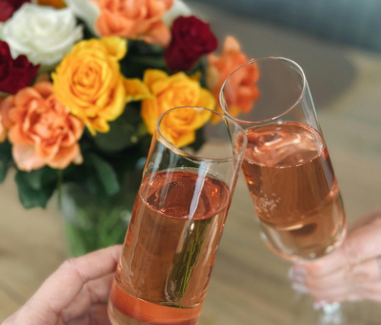 Two glasses of bubbly in front of a flower display.