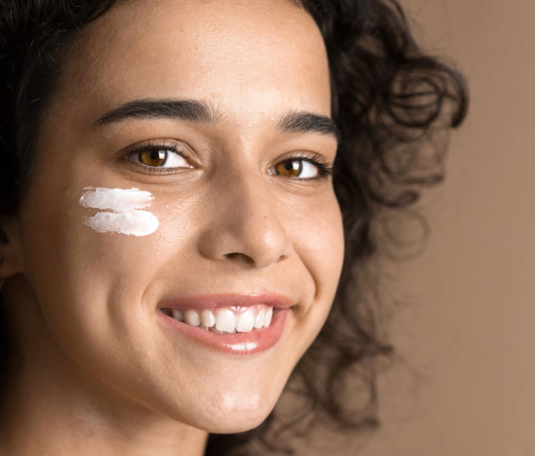 Girl smiling with skin cream on her cheek.