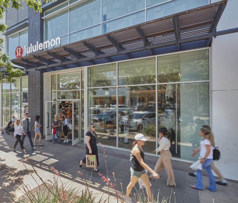 Customers walking with shopping bags in front of a lululemon store.