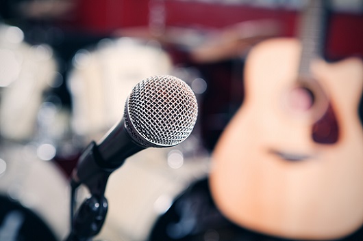 microphone with zoomed out blur of drums and acoustic guitar