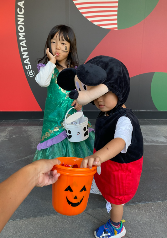 Little boy and little girl dressed up for Halloween eating candy.