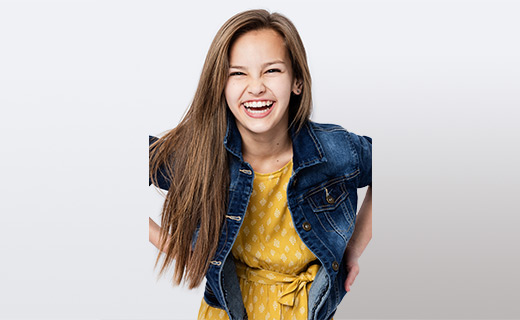 Young girl in a yellow dress and jean jacket smiling