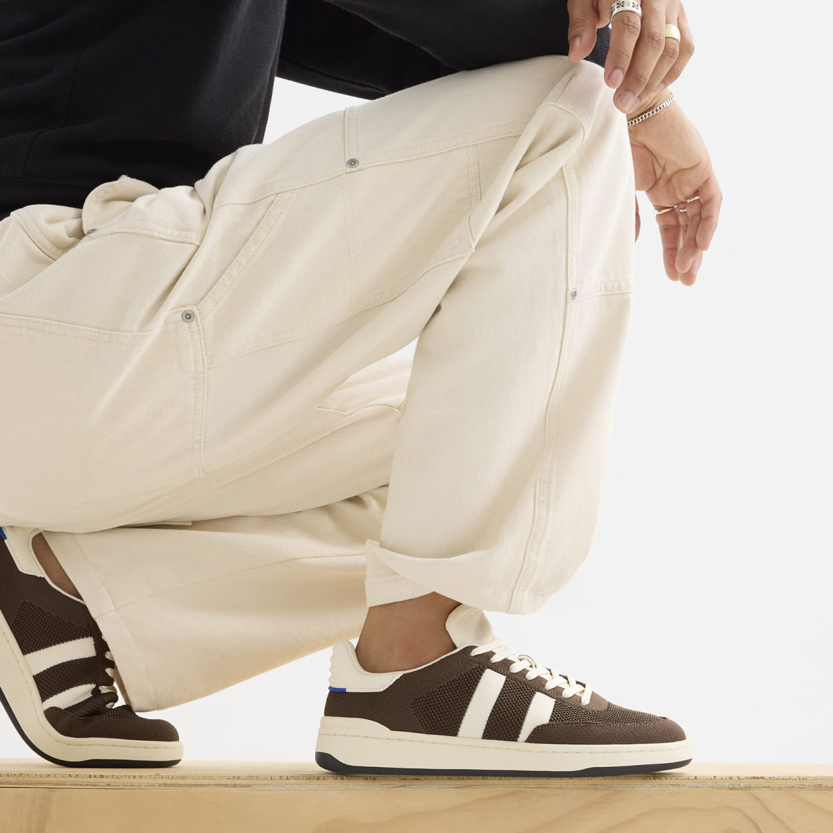 closeup of man crouched down so you can see his brown and white sneakers