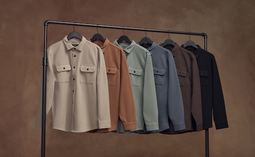long sleeve overjackets in multiple tan and dark colors lined up on a clothing rack