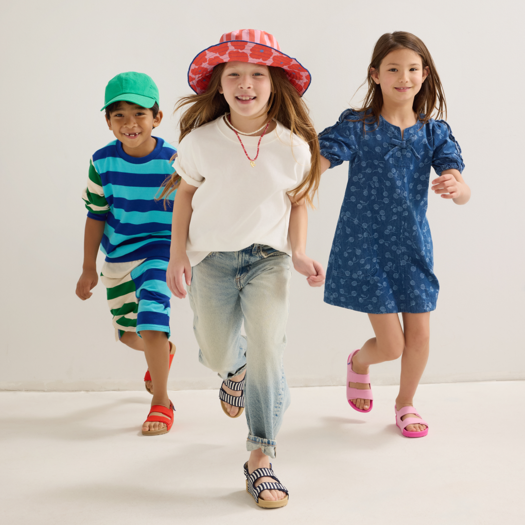 3 kids running towards the camera in summer clothing and smiling 