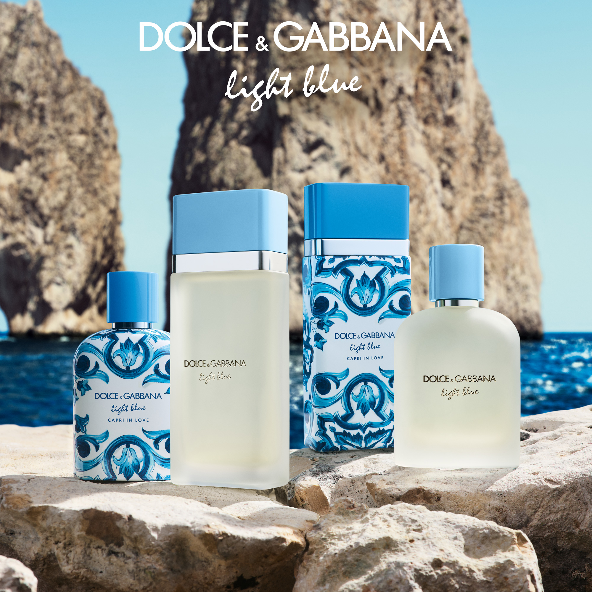 dolce & gabbana logo x light blue. perfume bottles displayed on a rock against a beach backdrop
