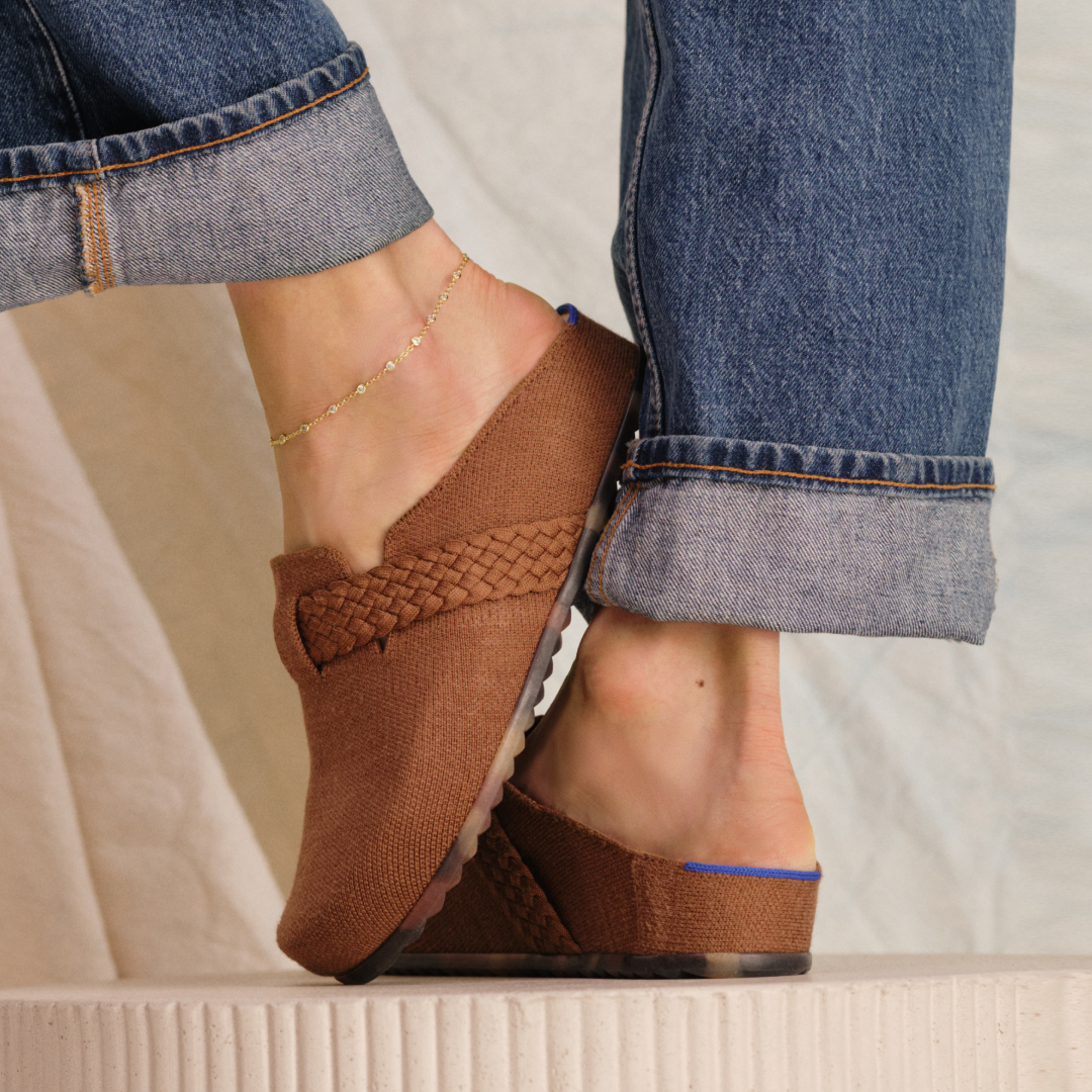 close of brown clogs on woman's feet with ankle bracelet