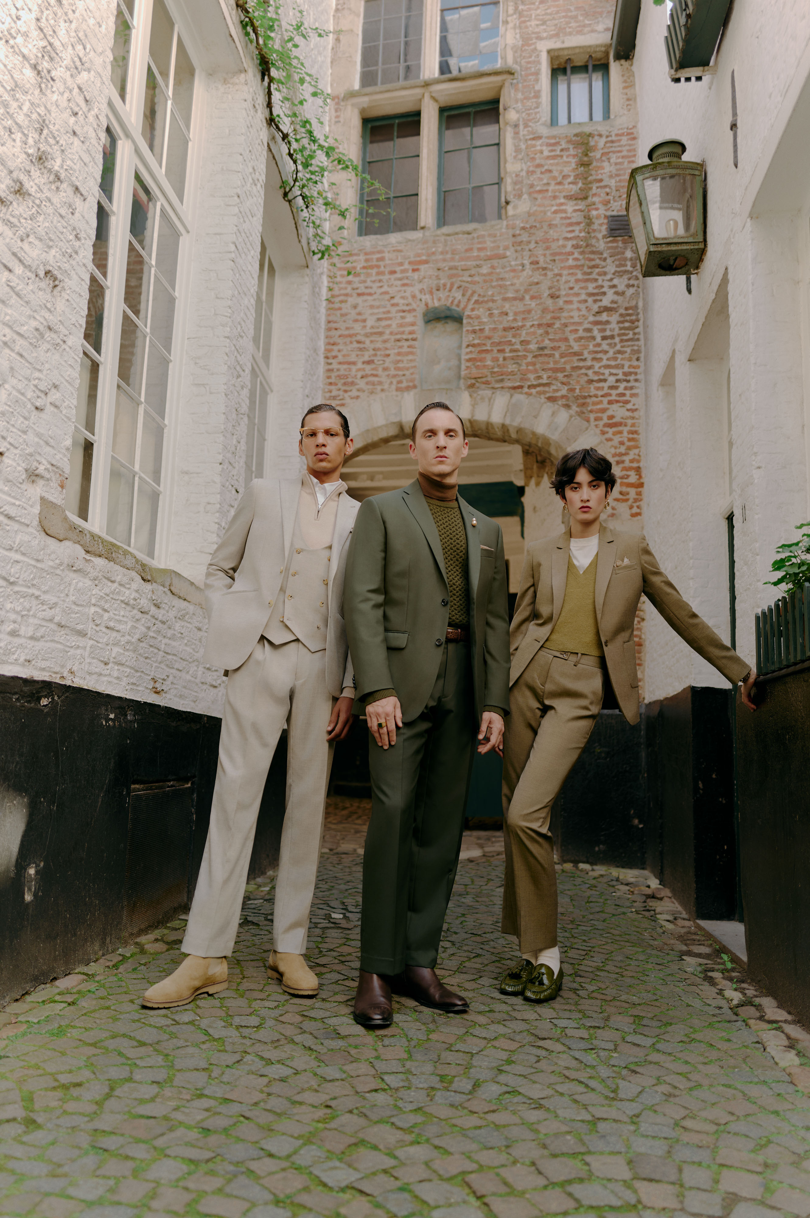 two guys and a girl wearing suites standing in an ally 