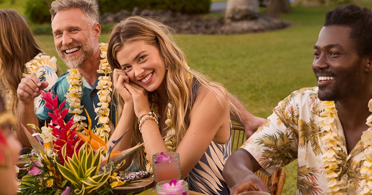 group of men and women smiling wearing hawaiian style shirts