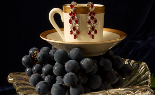 ruby and diamond earrings hanging from a coffee cup on top of grapes and a platter