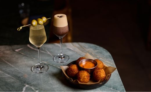 dirty martini and espresso martini and appetizer displayed on table 