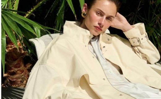 model smirking at the camera in a yellow jacket in front of a palm beach background