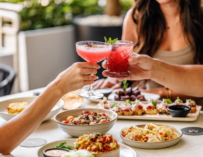 people cheers-ing drinks with a table full of food