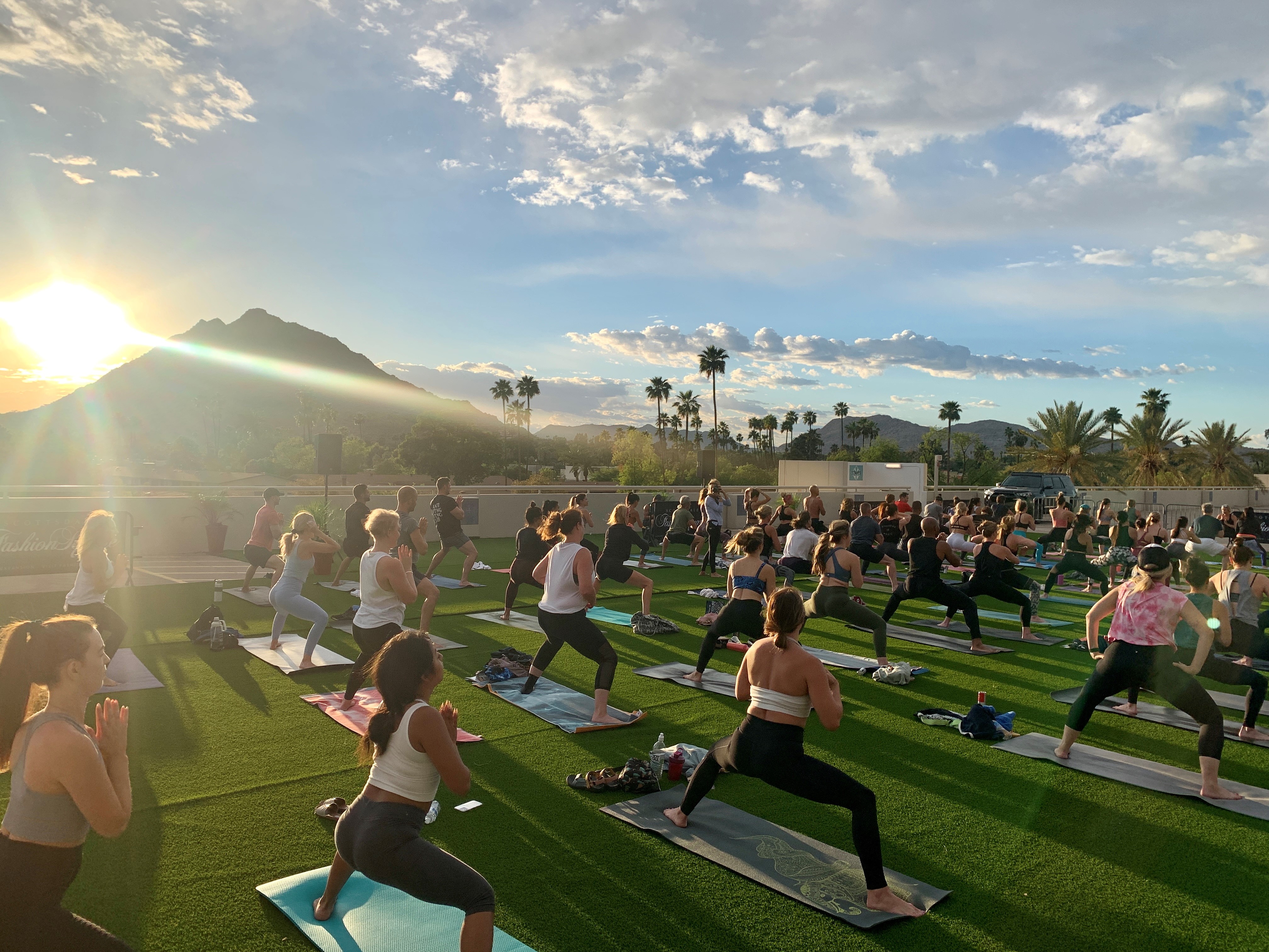 yoga event photo featuring number of men and women doing a warrior stance on yoga mats