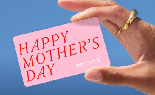 hand wearing gold rings holding a pink gift card that says happy mother's day with the rothy's logo