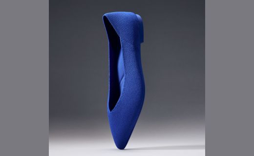 blue flat shoe against a grey background