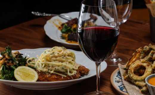 closeup of a table with pasta, chicken, glass of wine