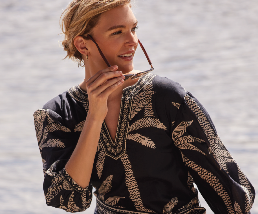 model smiling while putting on sunglasses