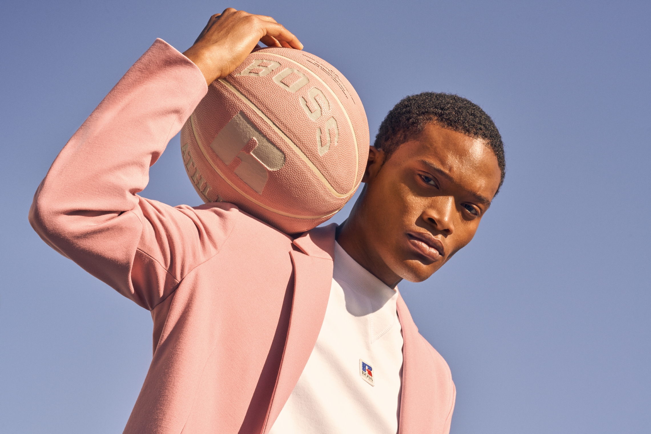 man in pink blazer holding pink basketball on shoulder