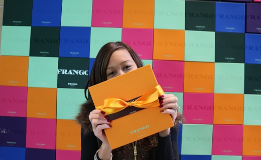 Girl with chocolate box standing in front of a wall of chocolate boxes