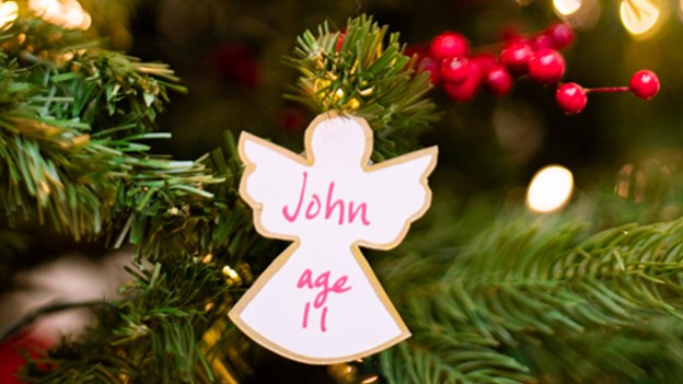 White angel ornament on a Christmas tree with "John age 11" written on it.