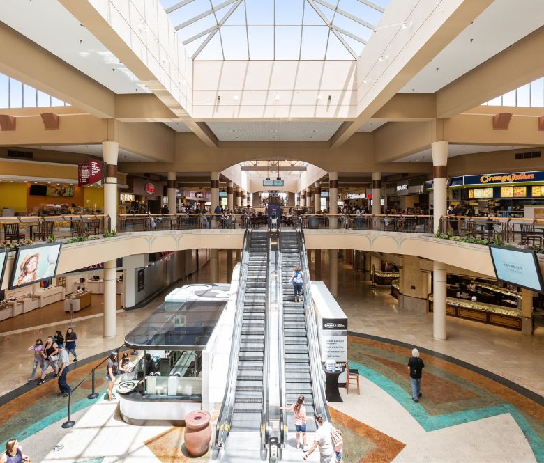 Interior view of Superstition Springs Center including stores, restaurants, escalators and shoppers. 
