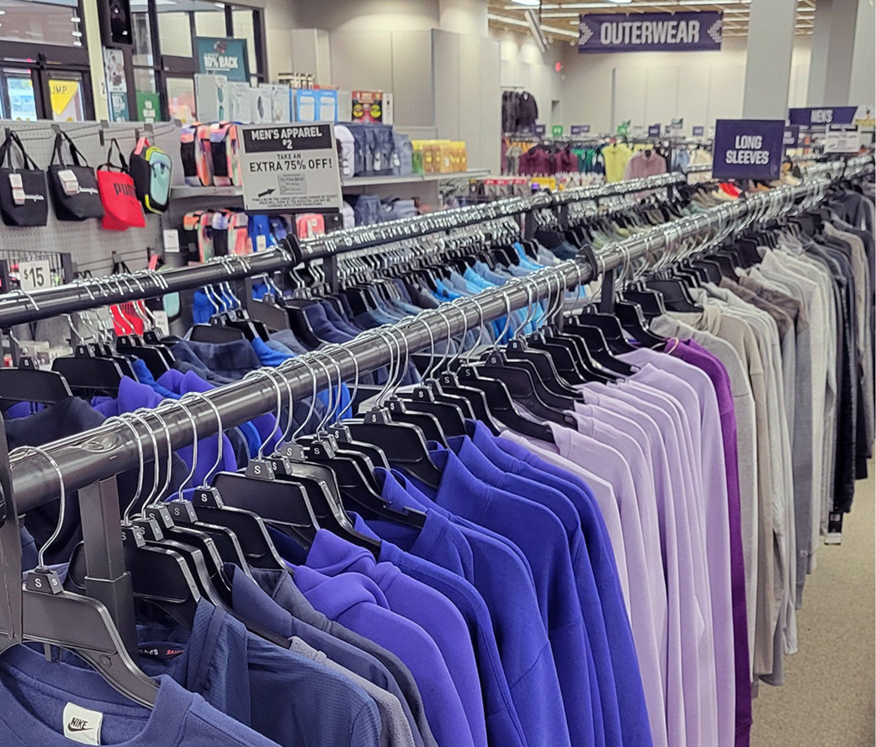 Racks of colorful apparel and backpacks in the background.
